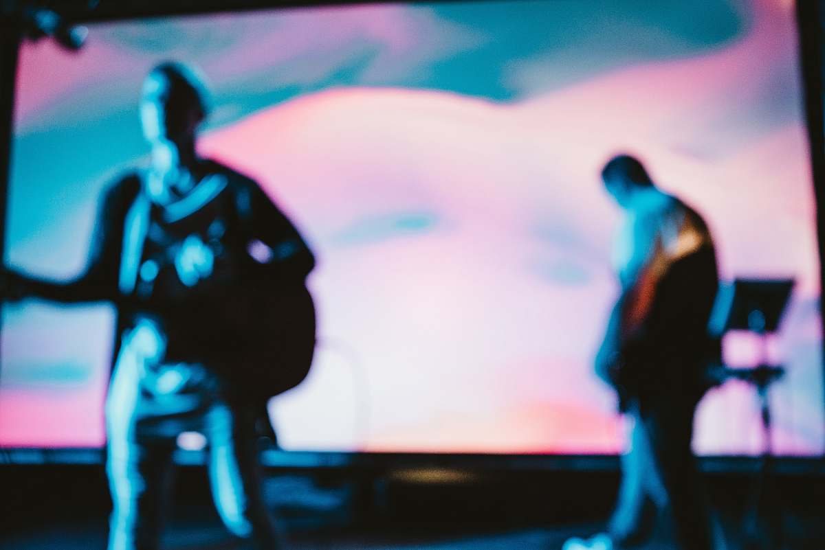 sing two men playing musical instrument on stage concert